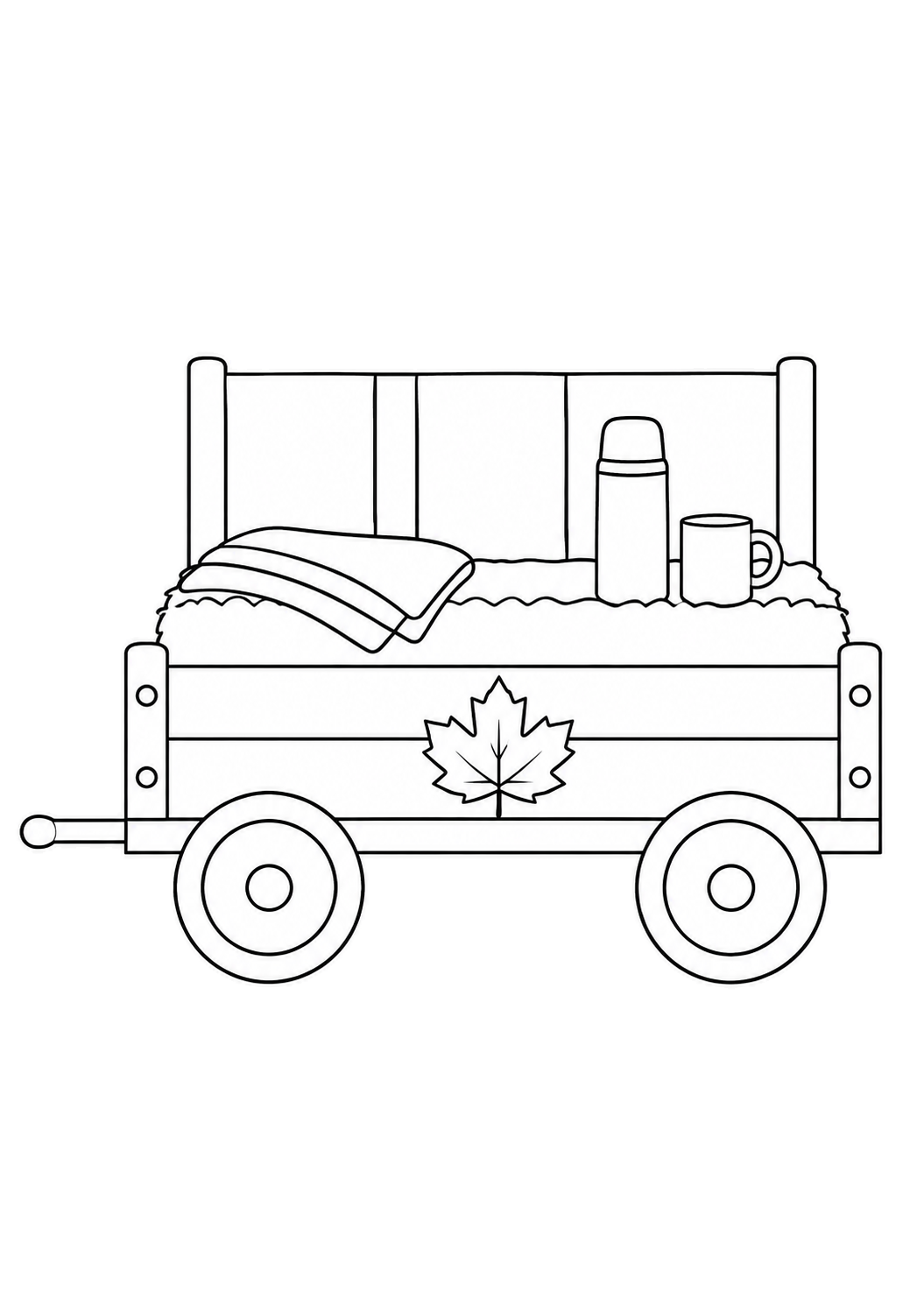 Carro di fieno fermo con thermos, tazza, coperta piegata e una foglia d’acero decorativa.